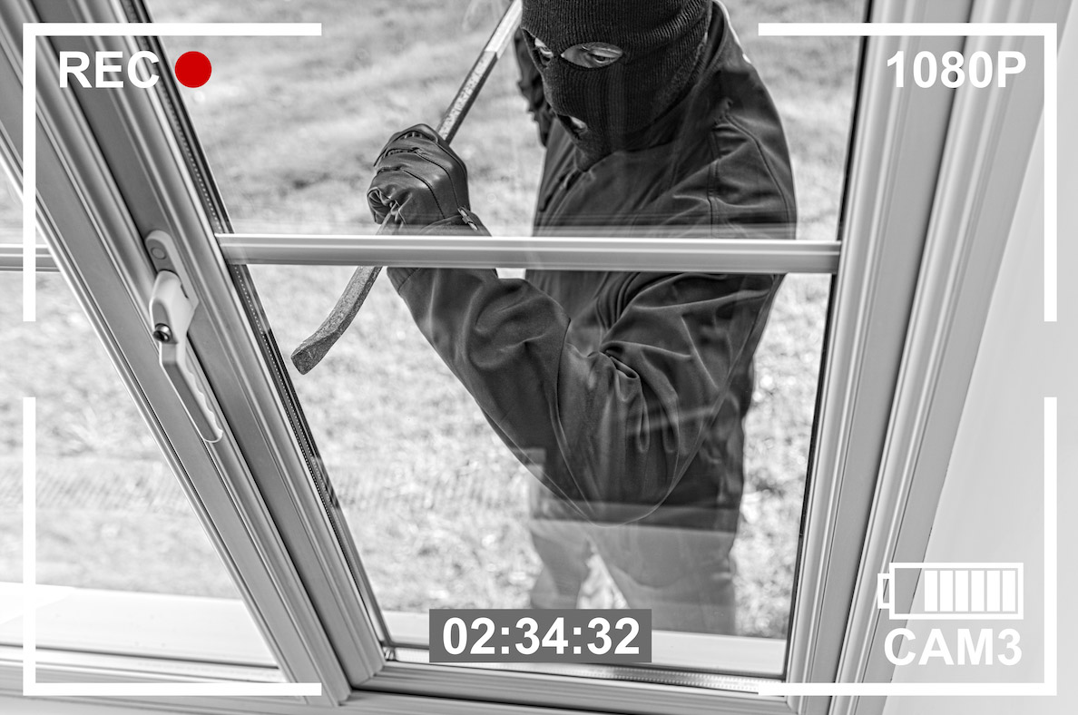 An intruder breaking into a home and being recorded by a security camera.