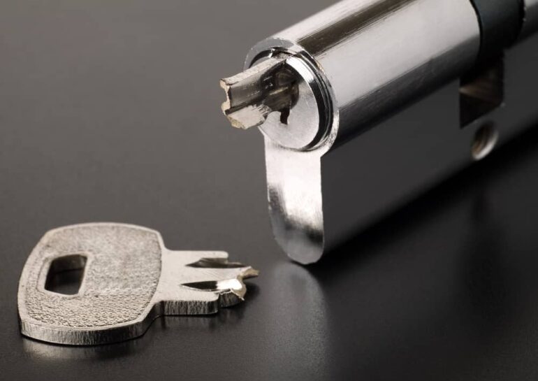 a lock with a broken key stuck inside while the other half of the lock is on the table