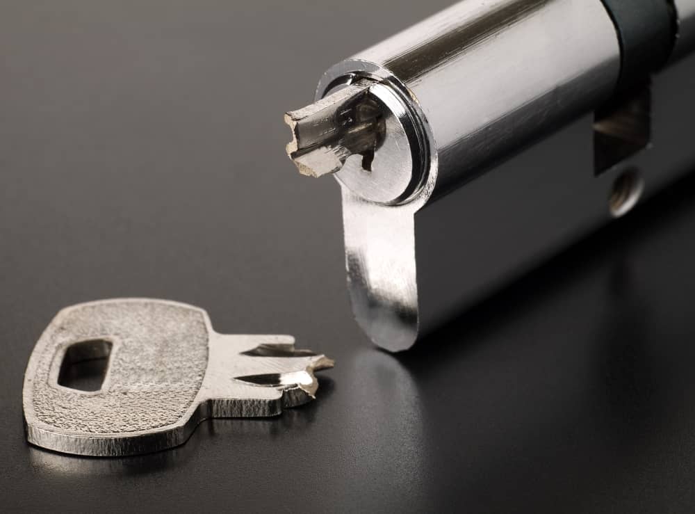 a lock with a broken key stuck inside while the other half of the lock is on the table